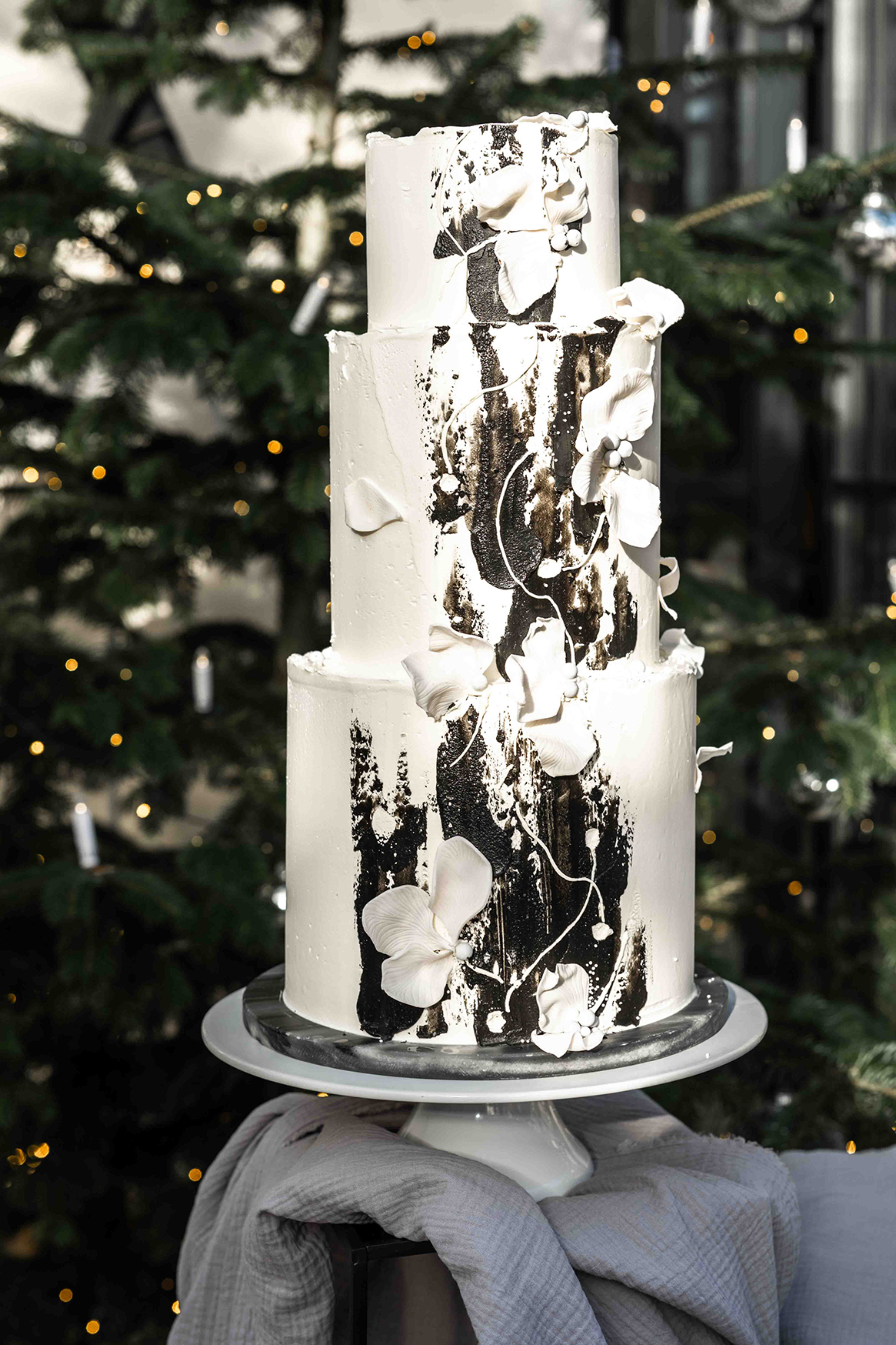 weiße Hochzeitstorte mit affinierten schwarzen Details und Zuckerrosen verziert
