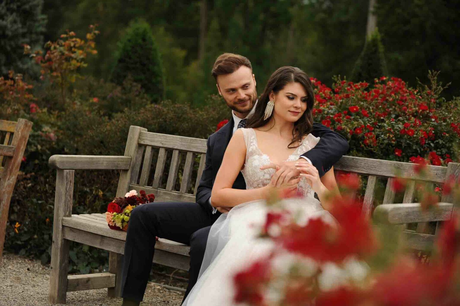 Brautpaar, Mann im schwarzen Hochzeitsanzug, Frau in weißem Hochzeitskleid im Herbst auf einer Parkbank im Freien im Schloss Eckertsau