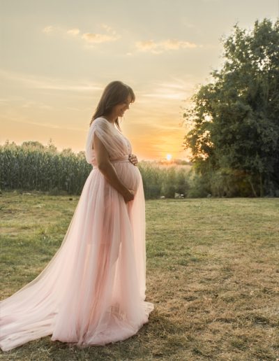 Werdende Mutter mit Babybauch im rosa Kleid von der Seite