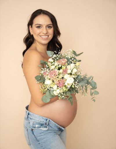 Werdende Mutter mit Babybauch mit Blumenstrauss