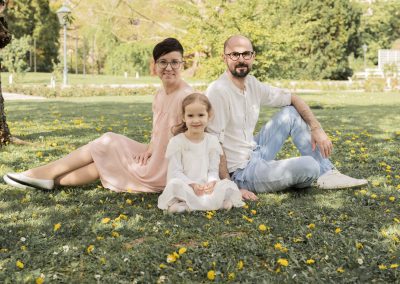 Familie mit Mutter, Vater und Tochter sitzen auf einer Blumenwiese