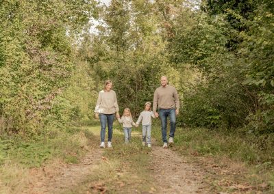 Familie spaziert durch einen Wald mit zwei Töchter