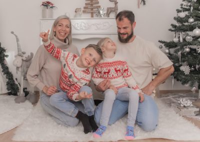 Familie mit Mutter, Vater, Sohn und Tochter vor einer Weihnachtsdekoration