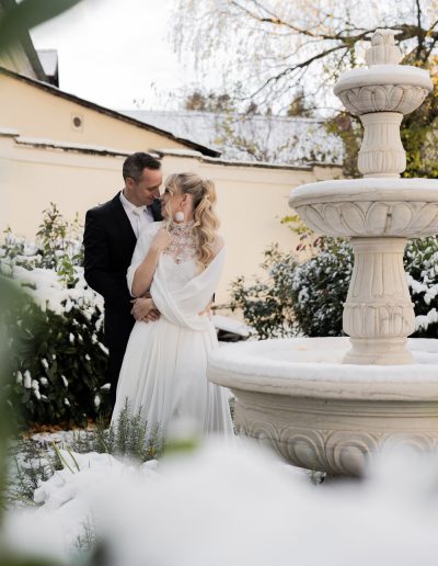 Hochzeitspaar im Schnee mit einem Brunnen