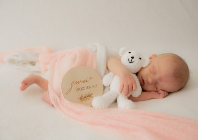 Neugeborenes Baby mit weißem Teddybär