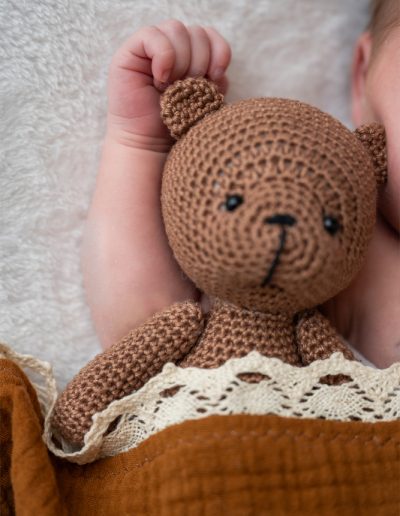 gehäkelter Teddybär im Babyarm