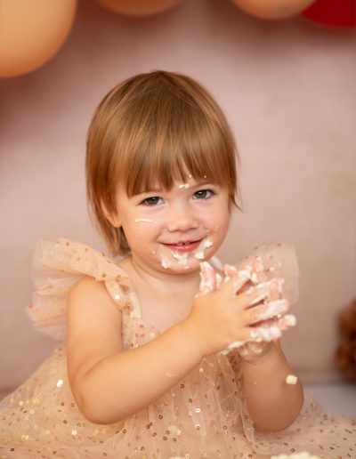 Kleines Mädchen mit Tortencreme im Gesicht und auf den Händen