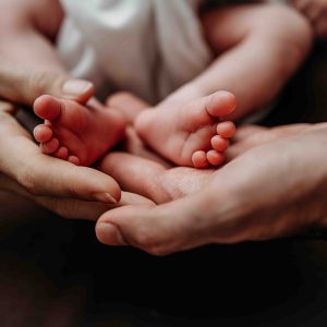 Babyfüsse und die Hände von Mama und Papa