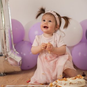 Babymädchen hat den 1 Geburtstag, Man sieht lila und weiße Luftballone