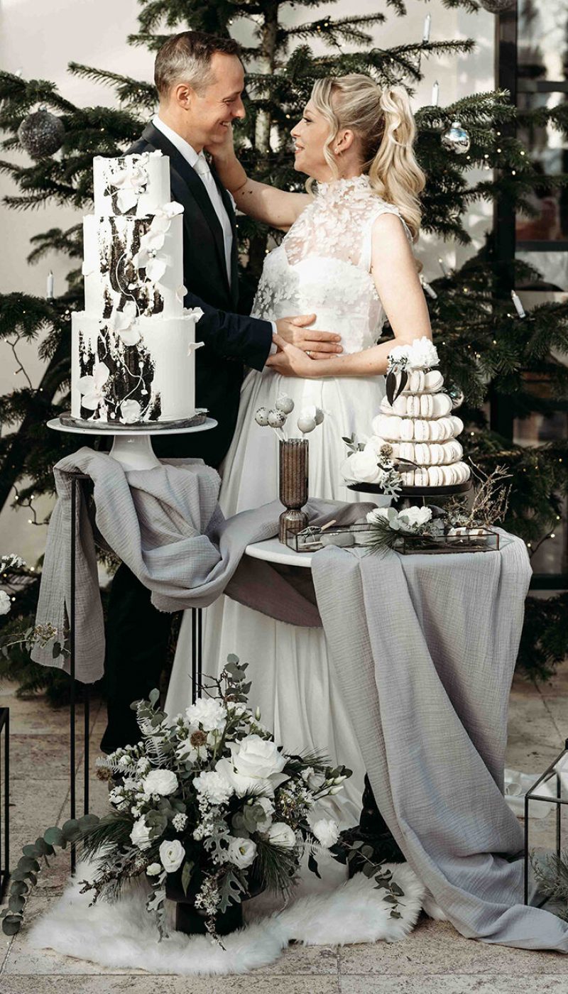 Brautpaar, Mann im schwarzen Hochzeitsanzug, Frau in weißem Hochzeitskleid vor der Hochzeitstorte im Schloss Gurhof